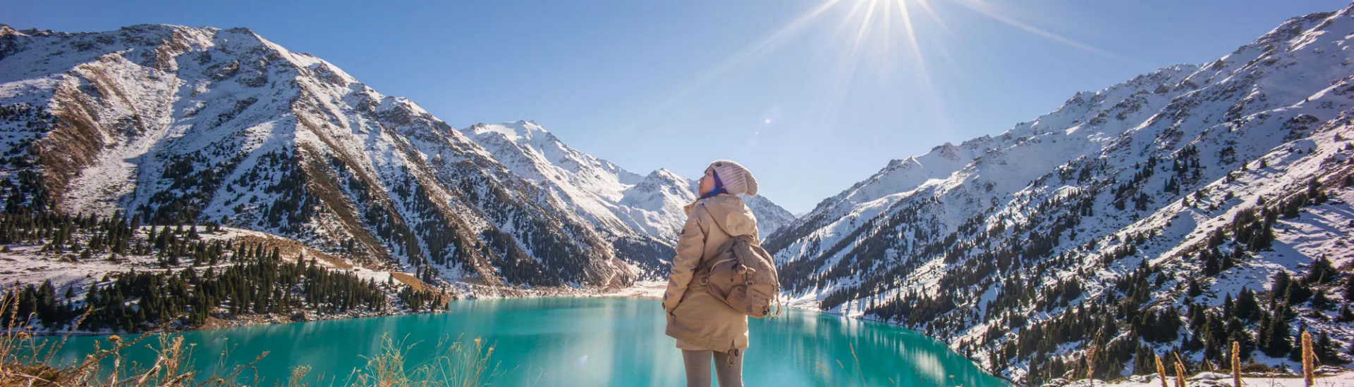 Frau erkundet Almaty See bei Sonnenschein zu Winterbeginn.
